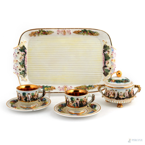 Servizio in ceramica Capodimonte composto da grande vassoio, due tazzine, due piattini e una zuccheriera con scene mitologiche a rilievo, XX secolo, misure massime cm 37x23, (segni di usura, difetti, scalfiture, cadute di doratura)