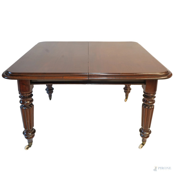 Tavolo in mogano, XIX secolo, piano sostenuto da montanti scolpiti e torniti poggianti su rotelle, dotato di 3 prolunghe, misura minima cm 76,5x125x120, larghezza prolunghe, cm 40 cad., (difetti)