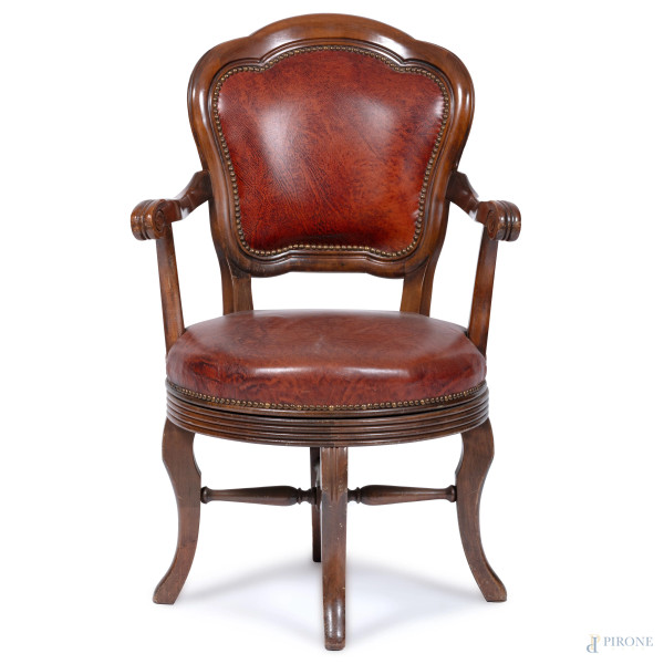 Poltrona girevole con struttura in legno. Schienale e seduta imbottiti e rivestiti in cuoio con borchie ai profili, XX secolo, cm 93,63,55, (segni di usura)