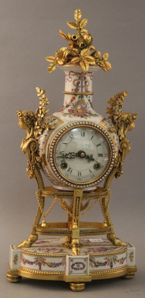 Orologio con cassa e base in porcellana a decoro di festoni, particolari e finiture in bronzo dorato, XX sec, h. 41 cm.