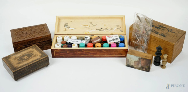 Lotto di cinque scatole diverse in legno intagliato e dipinto, di cui una contenente pigmenti da pittura ed una pedine per scacchi, misura max cm 7x30x10, XX secolo, (difetti).