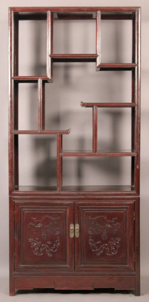 Libreria in legno laccato rosso a due corpi, parte superiore a giorno e parte inferiore a due sportelli incisi, Arte orientale, XX sec., cm 184 x 84 x 38.