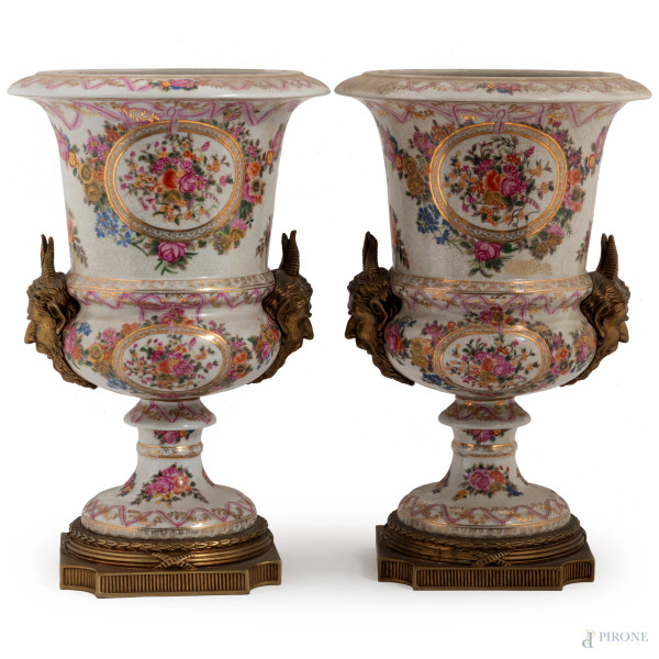 Coppia di vasi a cratere in ceramica decorata a motivi floreali con prese a guisa di teste di satiri e basi in bronzo dorato, XIX-XX secolo, altezza cm 41, (segni di usura)