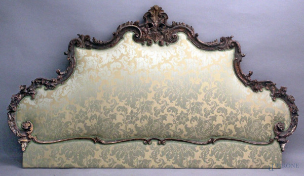 Testata da letto in legno intagliato a motivi di foglie d&#39;acanto, con imbottitura in stoffa verde fiorata, cm 119x210, XIX sec.