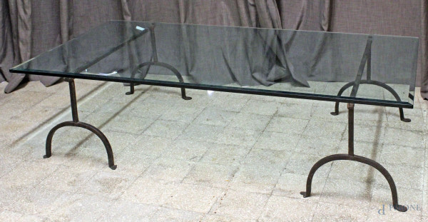 Basso tavolo linea rettangolare, XX secolo,  piano in cristallo, poggiante su coppia di montanti in ferro battuto, cm h 48x179,5x96, (difetti).