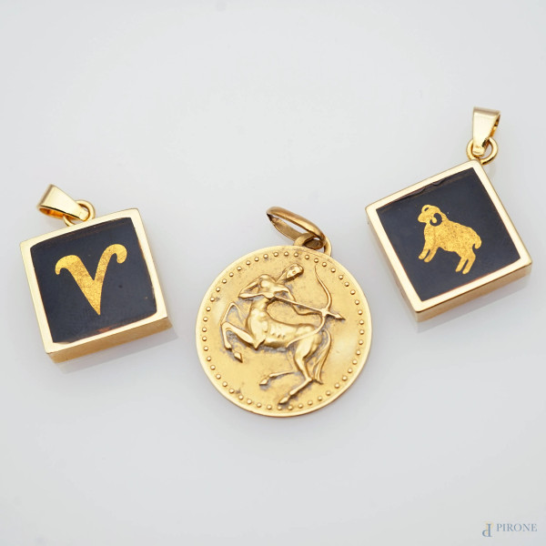 Lotto di tre ciondoli in oro giallo 18 kt e metallo dorato, decori raffiguranti segni zodiacali, diametro cm 2,4, peso netto dell'oro gr 5,6