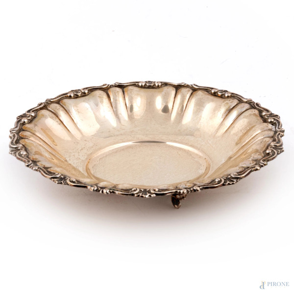 Centrotavola dal profilo orlato in argento 800/000 sbalzato e cesellato poggiante su tre piedini a ricciolo, cm 5x23, peso gr 220