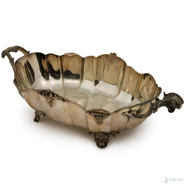 Centrotavola in argento di forma ovale con profilo polilobato con due manici e poggiante su quatt...