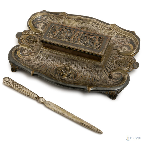 Calamaio in metallo argentato a foggia di sarcofago con bassorilievo di putti su vassoio polilobato e cesellato poggiante su quattro piedini, con taglia carte, Inghilterra, E&Co, primo XX secolo, misure massime cm 6,5x27x19, (difetti)