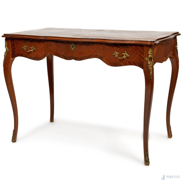 Scrivania impiallacciata in satinwood dal profilo mosso e inserti bronzei con cassetto al fronte e gambe mosse. XX secolo, cm 74,5x101x60, (scalfiture, usura del tempo)
