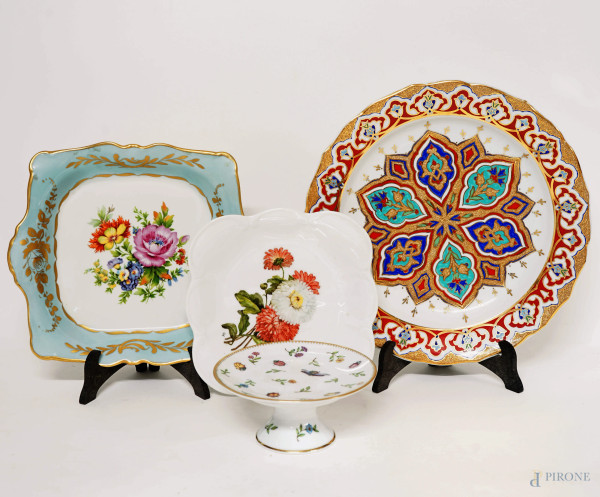 Lotto di tre piatti ed un'alzatina in porcellana policroma, manifatture diverse, XX secolo, diametro ma cm 28,5