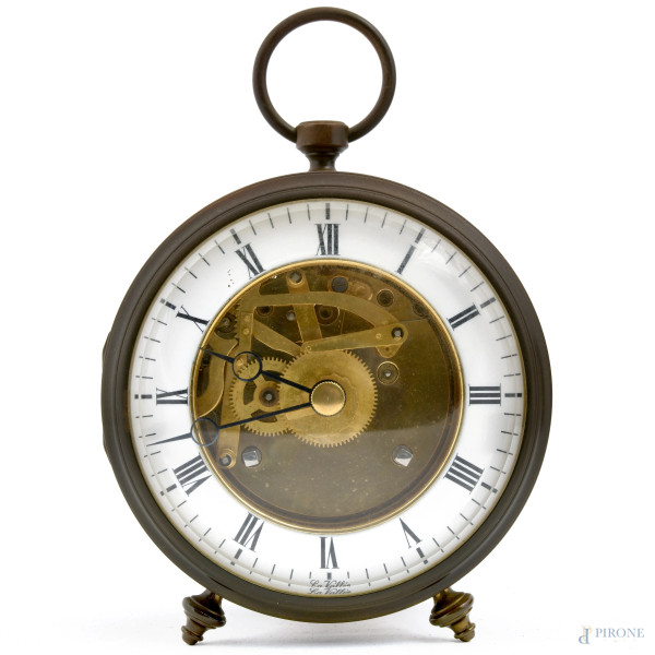 Orologio sveglia da tavolo con struttura circolare poggiante su tre piedini. Quadrante in smalto a numeri romani con meccanismo a vista, cm 16x11, (da revisionare)