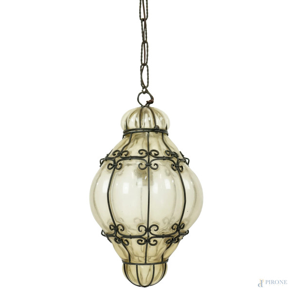 Lanterna veneziana in vetro soffiato di Murano, catena e gabbia in ferro battuto,  cm 112 circa, XX secolo.