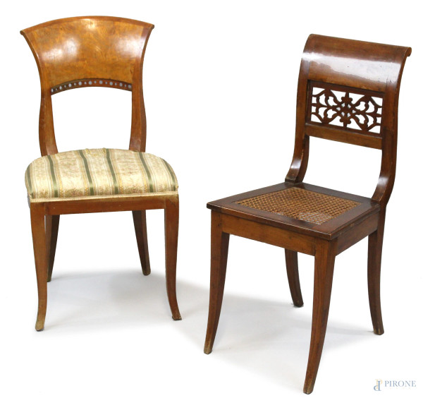 Lotto di due sedie in legni ed epoche diverse, schienali traforati, sedute in paglia ed in tessuto beige e verde, poggianti su quattro gambe a sciabola. 
