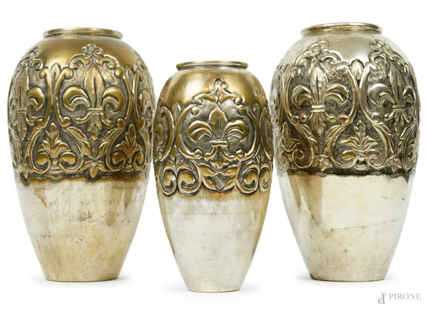 Trittico di vasi in metallo argentato, sbalzato e cesellato a motivi di foglie e gigli, XX secolo, alt. max cm 25, (difetti)