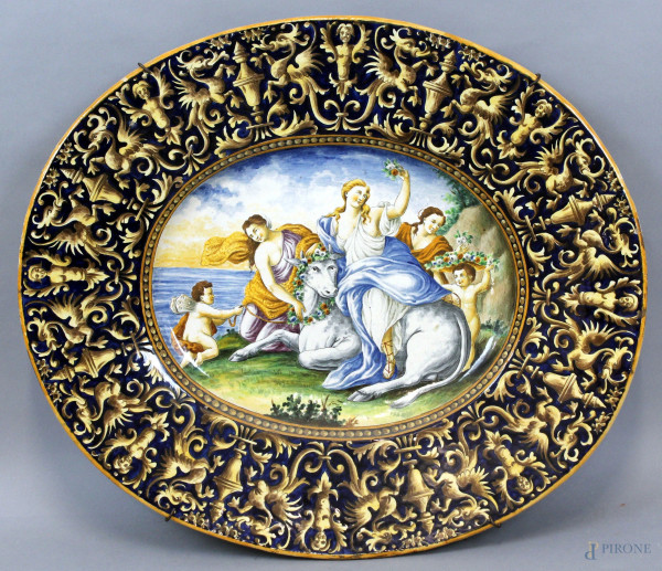 Grande piatto di linea ovale in ceramica policroma, con decoro raffigurante il Ratto di Europa, bordo a grottesche e motivi vegetali, cm 63x54, XIX secolo, (difetti)