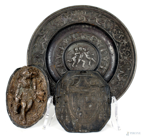 Lotto composto da un bassorilievo raffigurante Diana, un piattino con putti e motivi floreali  ed una medaglia con stemma araldico, diam. max cm 18,5, (difetti)