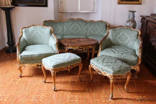 Salotto di fine Luigi XV, composto da divano, due poltrone, due panchette in legno intagliato e dorato con sedile e dorsale in stoffa verde, completo di tavolino ovale.