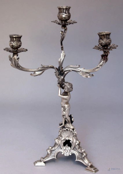 Candeliere in argento a tre fiamme sorretto da putto poggiante su base a tripode, H. 38 cm., gr. 1340.
