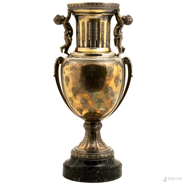 Grande vaso biansato in argento con prese a guisa di putti su foglie d'acanto a sorreggere l'orlo. Al corpo centrale delicate incisioni a guisa di rose. Peso lordo gr 5.480; altezza cm 50, (difetti)
