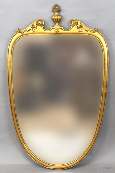 Specchiera a forma di scudo in legno intagliato e dorato, cm h 105x64, XX secolo.