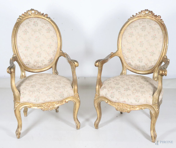 Coppia di poltrone in legno intagliato e dorato con seduta e schienale imbottiti e rivestiti in tessuto floreale nei toni dell'oro e panna, XIX secolo, cm 105x64xx64, (segni di usura, scalfiture, cadute di doratura, rotture, restauri, difetti)