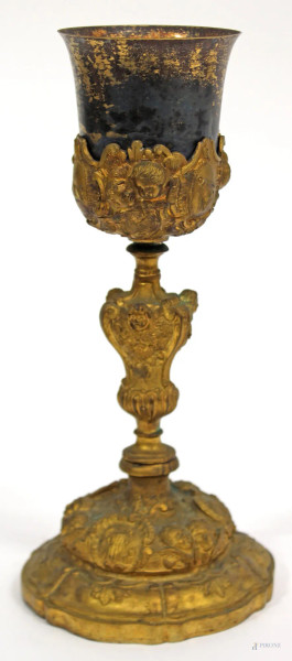 Calice in metallo dorato e sbalzato con volti di amorini a rilievo, XIX sec., H 30 cm.