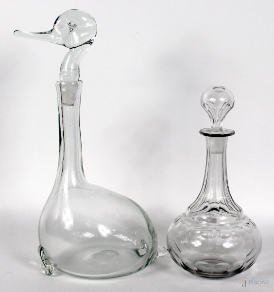 Lotto di due bottiglie in vetro trasparente, forme diverse, altezza max 38 cm.