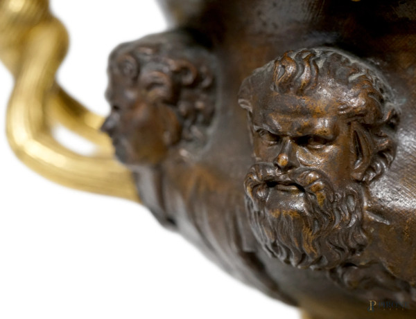 Coppa in bronzo patinato e dorato con pareti cesellate a sequenza di teste virili, due anse a ram...