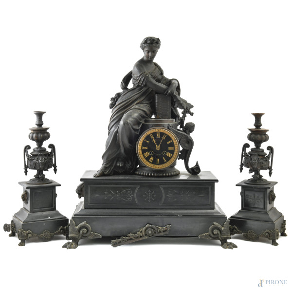 Trittico da camino in marmo nero e inserti in bronzo composto da orologio con quadrante circolare a numeri romani sormontato da scultura di Sibilla e da coppia di alzate portaceri, XX secolo, misure massime cm 58x47x23,5, (segni di usura, difetti, da revisionare)