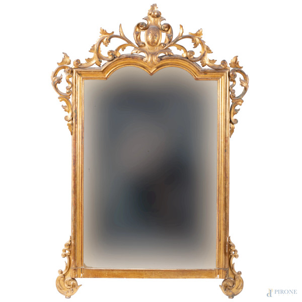 Specchiera in legno dorato e intagliato a volute vegetali e stemma araldico apicale, XIX secolo, cm 168x111, (segni di usura, perdita di doratura, scalfiture, difetti)