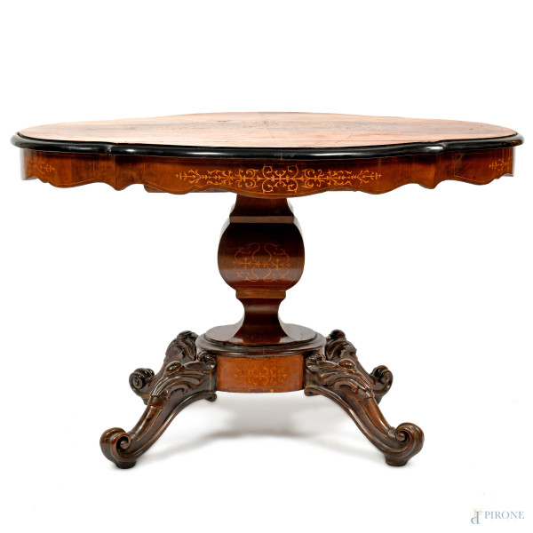 Tavolo con piano sagomato finemente intarsiato con decori fitomorfi in legni da frutto. Bordo profilato in legno laccato nero. XX secolo, cm 75x120x48, (difetti)