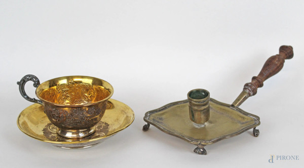 Lotto composto da una bugia in argento ed una tazzina da tè con piattino in metallo argentato, decori floreali incisi, lunghezza max cm 22,5, epoche diverse, (segni del tempo).
