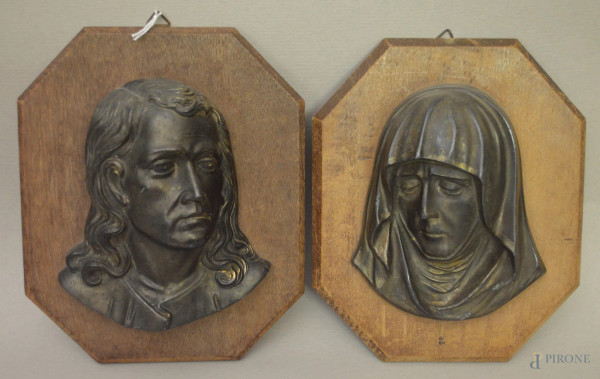 Coppia fusioni in metallo raffiguranti due volti su supporti ottagonali in legno, h. 14 cm.