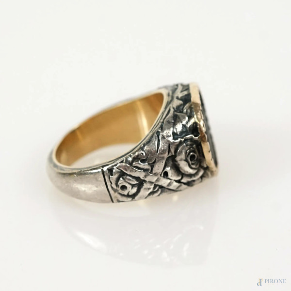 Anello da uomo in oro e argento con moneta incastonata, decori a rose e nastri intrecciati, XX se...