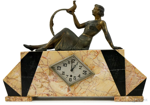 Orologio da tavolo Art Dèco, lastronato in marmi policromi, sormontato da figura femminile con volatile in metallo dorato, cm h 39,5x56x10, (difetti, meccanismo da revisionare)