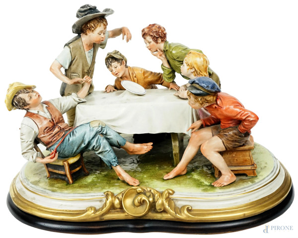 A tavola, gruppo in porcellana policroma Capodimonte, cm h 39x51x38,5, firmata B.Merli, (lievi difetti).