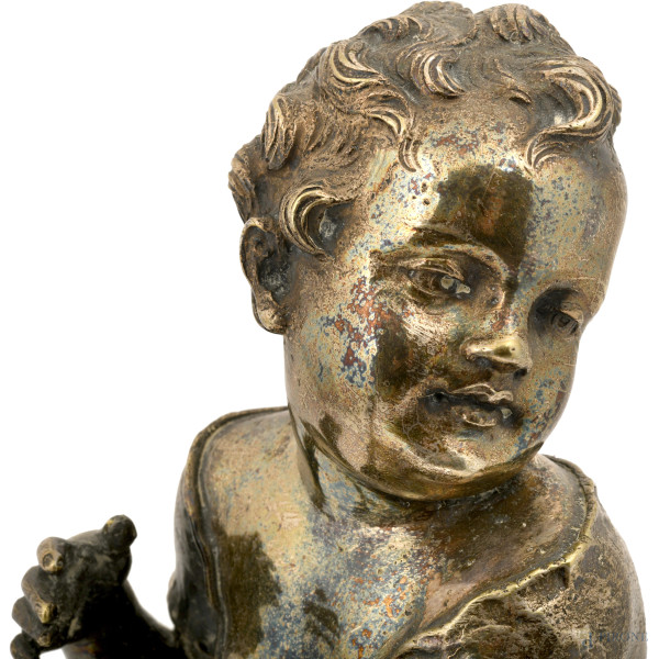 Scultura in metallo argentato raffigurante bambino a guisa di putto che suona uno strumento a cor...