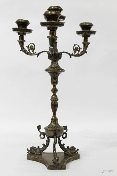 Candeliere in argento cesellato a quattro fiamme poggiante su tripodi, H 40, gr 1360.