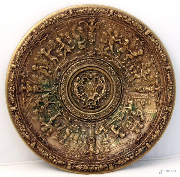 Piatto di linea tonda in bronzo sbalzato a tutto decoro di scena di allegoria di putti musicanti con stemma araldico, XIX sec., diametro 38 cm.