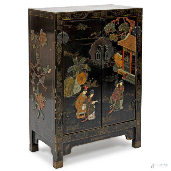 Mobile in legno laccato nero con fronte a doppio sportello e interno a doppio ripiano, decorato con motivi floreali e geometrici dorati. Al fronte scena di genere policroma a rilievo, cm 79x54x28. Giappone, XX secolo, (difetti)