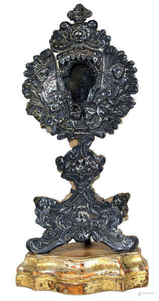 Reliquario del XVIII secolo, in legno rivestito in lamina d'argento sbalzata e cesellata a motivi di angioletti e rocailles, cm h 48, (difetti).
