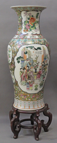 Vaso in porcellana policroma a tutto decoro di fiori e dignitari poggiante su base in tek, arte orientale, XX sec., H 110 cm.