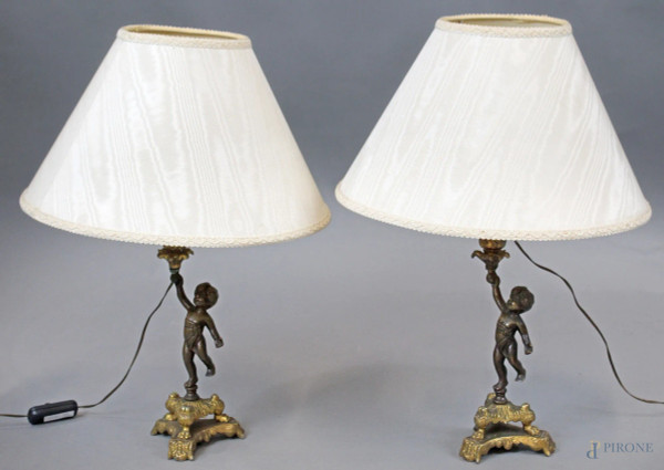 Coppia di lampade da tavolo in metallo dorato e brunito, fusti a forma di putti, base a tripode con piedi ferini, altezza cm. 49, XX secolo.