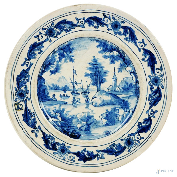 Piatto in ceramica  bianco e blu, decoro raffigurante paesaggio marino con figure, tesa a motivi floreali, diam. cm 24,5, XVIII secolo, (sbeccature).