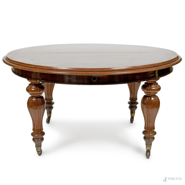 Tavolo in mogano allungabile con piano circolare poggiante su gambe tornite con rotelle. Corredato da prolunga di cm 53. XIX secolo, cm 79x150; aperto cm 79x203, (segni di usura, scalfiture, graffi, difetti)