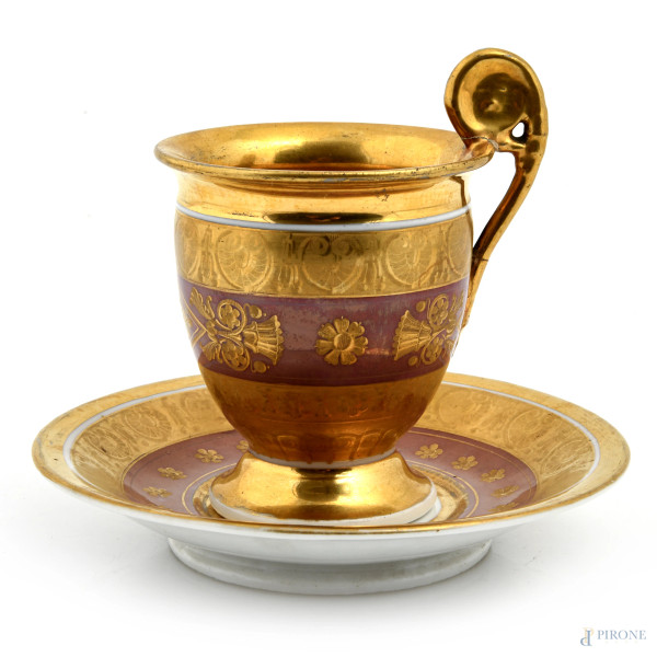 Lotto composto da tazzina e piattino in porcellana decorata nei toni dell'oro del rosa, XX secolo, diametro piattino cm 14, altezza cm 11, (segni di usura, sbiaditure, cadute di smalto, rotture, restauri)