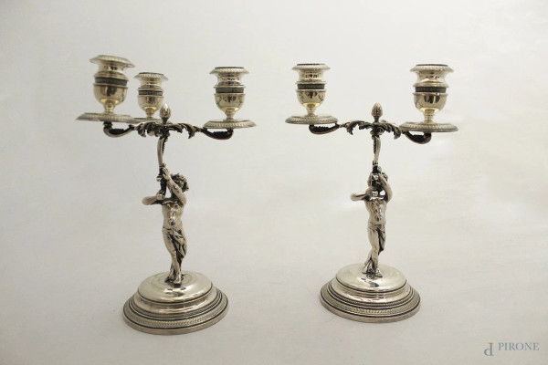 Coppia candelieri in argento cesellato a tre luci, sorretti da putti.