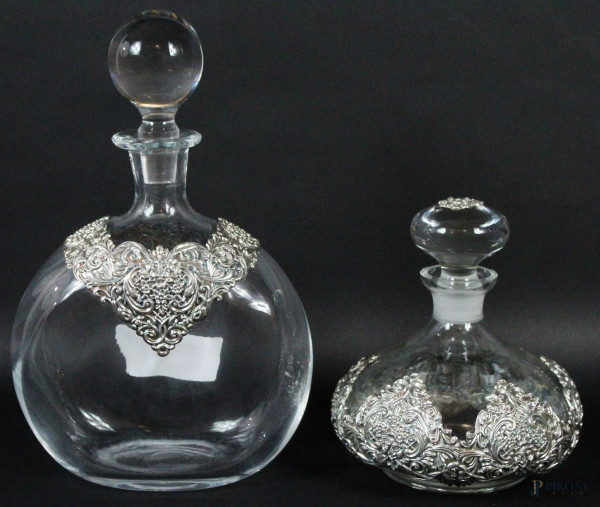 Due bottiglie in cristallo con decorazioni applicate in argento sbalzato e cesellato, altezza max cm 27,5