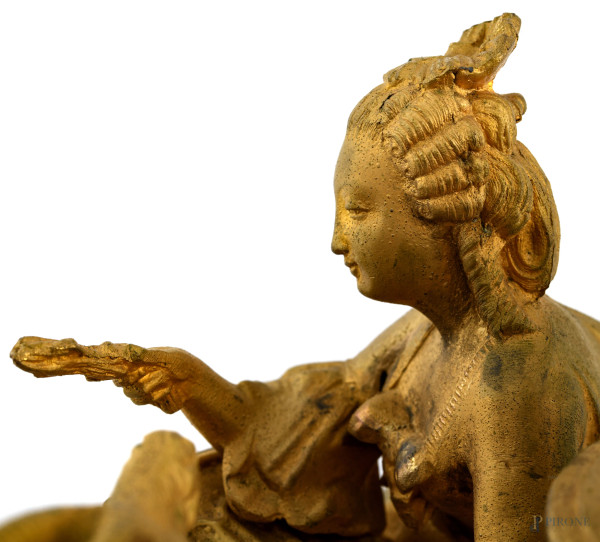 Orologio in antimonio dorato con quadrante a smalto e numeri romani. Sculture apicali di dama con...